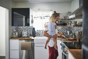 un uomo che tiene in braccio una bambina in una cucina