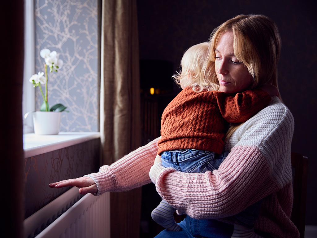 Madre con figlio che controlla il caldo dal radiatore a casa