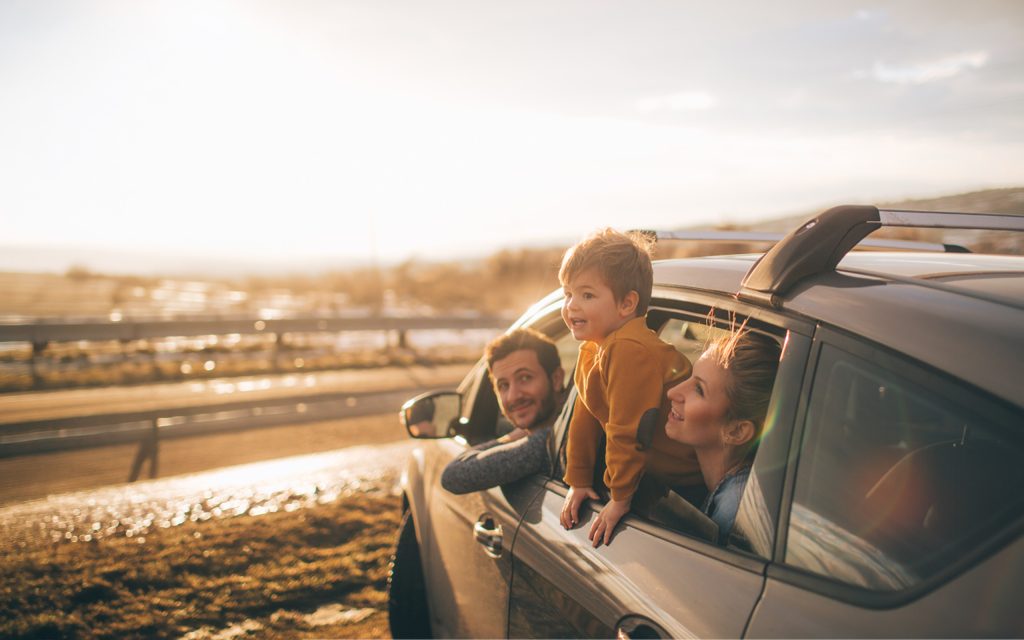 Bambino insieme alla propria famiglia osserva il panorama dal finestrino dell'automobile in una pausa del viaggio